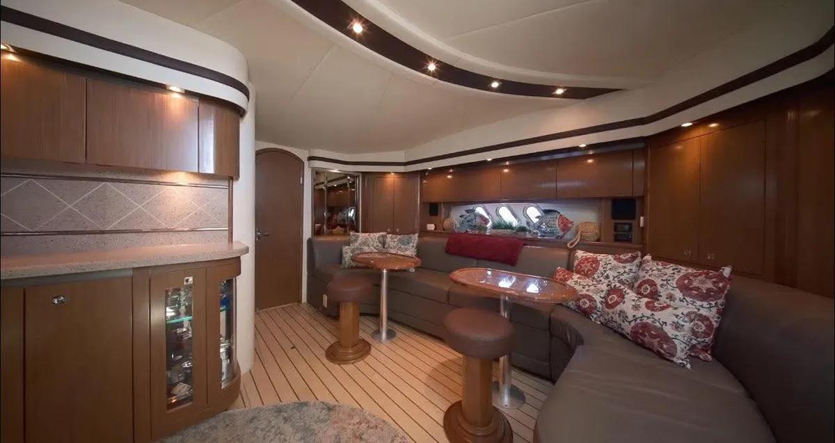 Salón interior del Cruiser Yachts 50', con piso de teca, sofá de cuero en U y dos mesas
