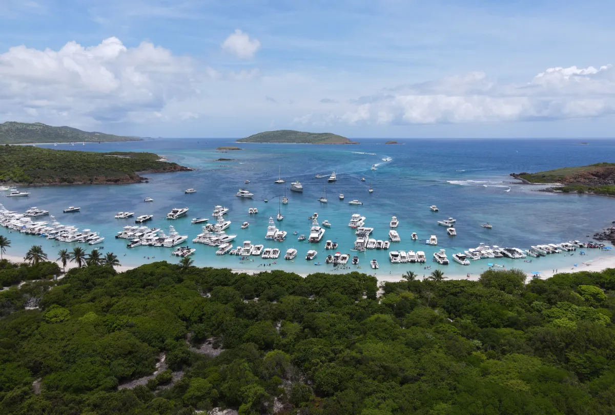 Vista aérea de un fondeadero lleno de botes frente a una playa de arena blanca en Culebrita