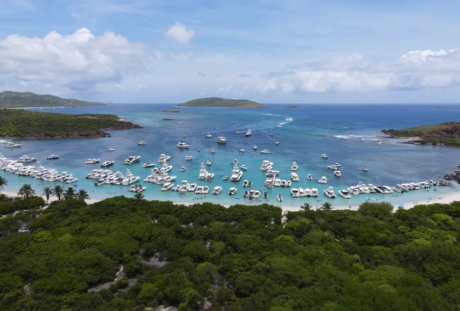 Vista aérea de un fondeadero lleno de botes frente a una playa de arena blanca