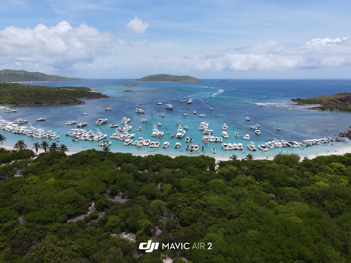 Vista aérea de un fondeadero lleno de botes frente a una playa de arena blanca en Culebrita