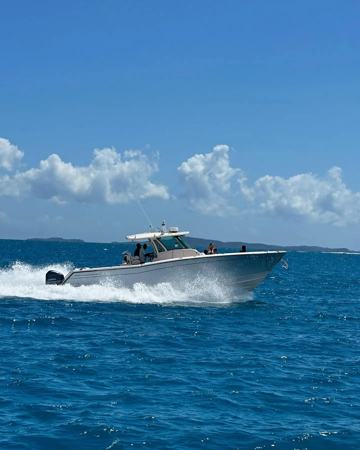 Bote Grady-White de Sea Life Charters navegando con pasajeros a bordo y una isla al fondo