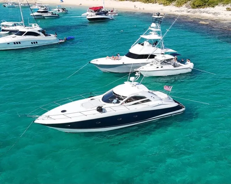 Vista aérea del Sunseeker 60' de casco azul marino fondeado en agua turquesa
