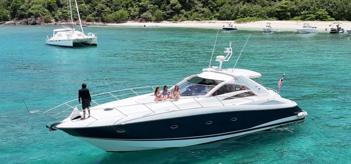 El Sunseeker 60' fondeado frente a la playa con pasajeros en la proa y en la bañera